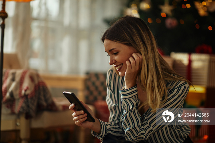 Woman using cellphone during Christmastime at home