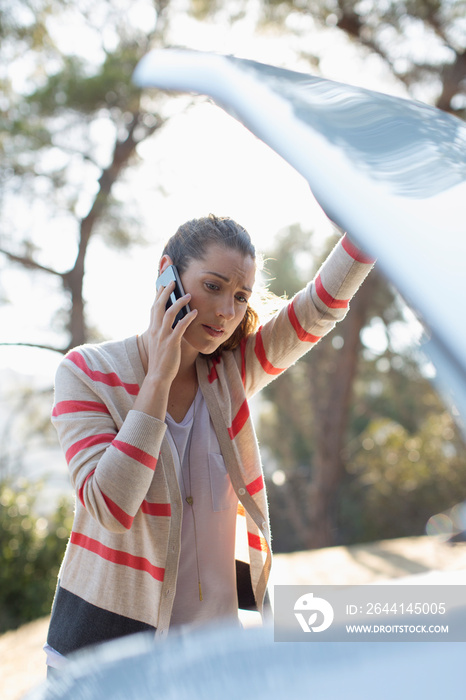 Frustrated woman with smart phone calling for help with car breakdown