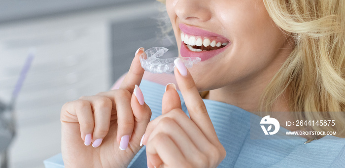 Unrecognizable female patient holding invisible braces or trainer, panorama