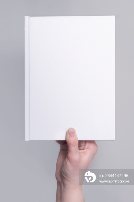 手上的白色精装书封面模型。适用于设计演示