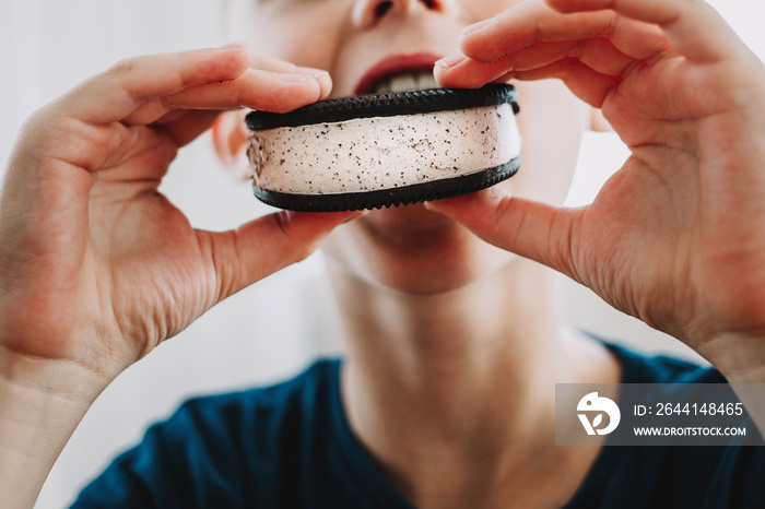 Close up of young boy eating ice cream sandwich.