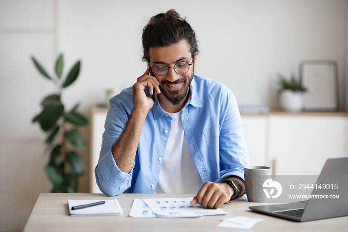 Freelancer Guy Checking Papers And Talking On Cellphone, Working At Home Office