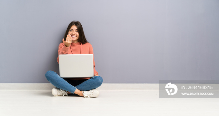 Young student girl with a laptop on the floor inviting to come