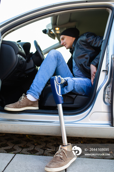 Young man with prosthetic leg driving car. Selective focus.