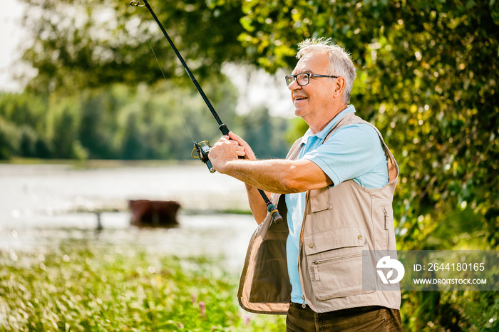 Happy senior man is fishing on sunny day.