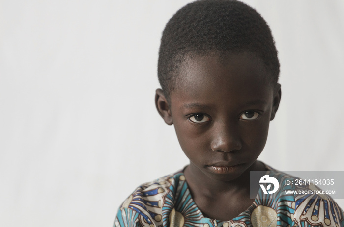 愤怒的非洲小男孩被隔离在白色衣服上，露出脸拍照