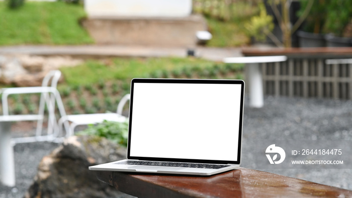 Mock up laptop computer with Wie display on wooden table in the garden.