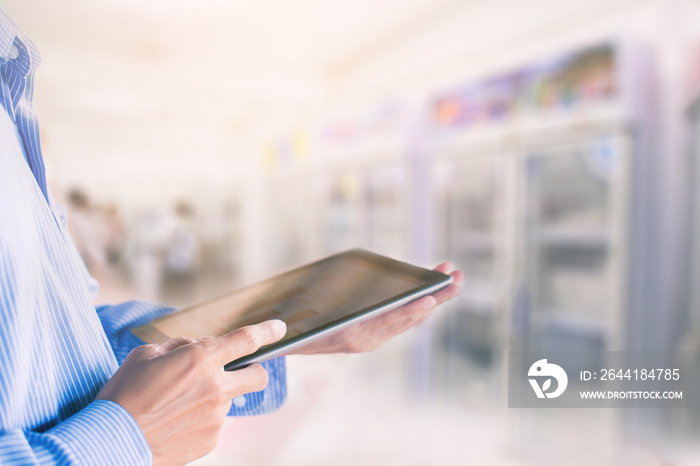 The manager uses a tablet to check stock products in supermarket.