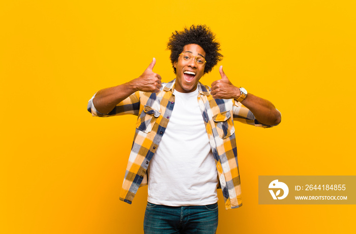 young black man smiling broadly looking happy, positive, confident and successful, with both thumbs 