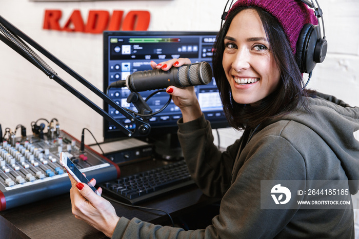 Beautiful happy young female radio host broadcasting