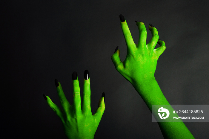 Green hand with black fingernails. On a black background.