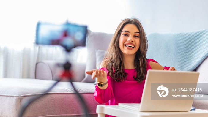 Young woman looking at camera while working on laptop. Young photographer with her camera and laptop