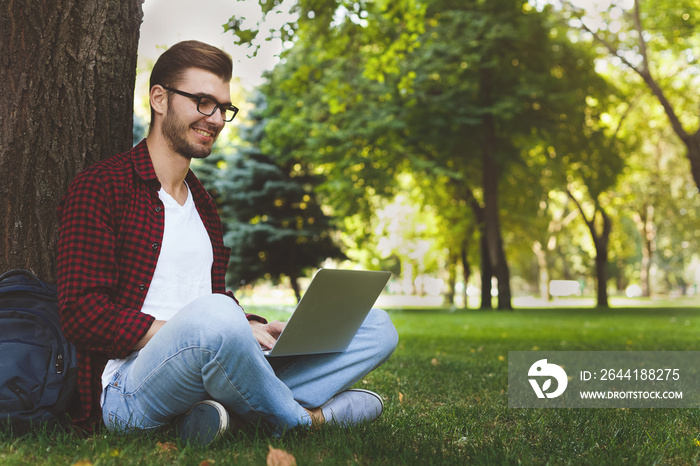 A smiling man with laptop outdoors