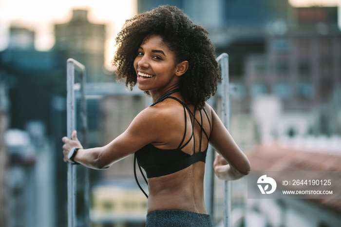 Portrait of female athlete standing on rooftop looking back