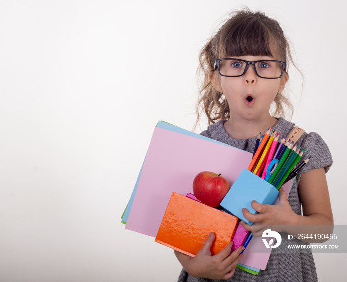 Shocked clever child in eyeglasses holding school supplies. Back to school concept. Space for text, 