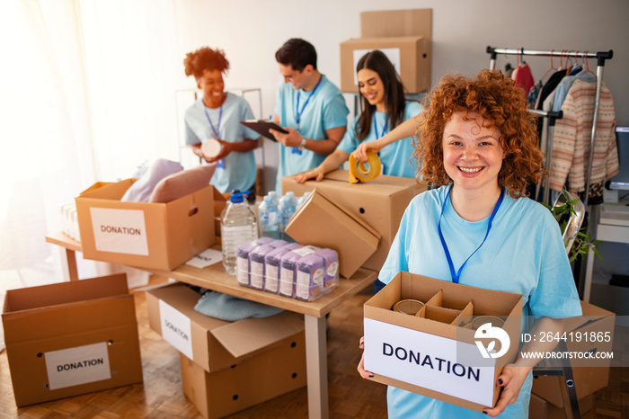 Happy volunteer looking at camera. Woman organizes food and clothing drive. She is smiling at the ca