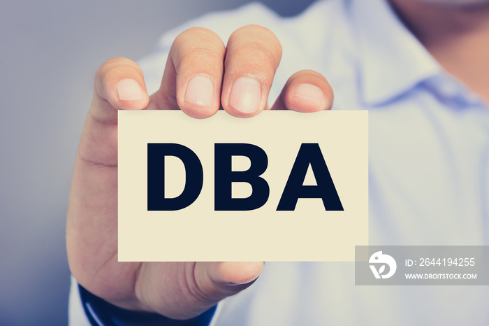 DBA letters (or Doctor of Business Administration) on the card shown by a man