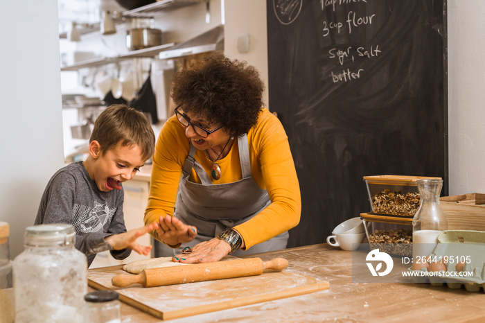 young boy preparing pizza dough with her grandparent