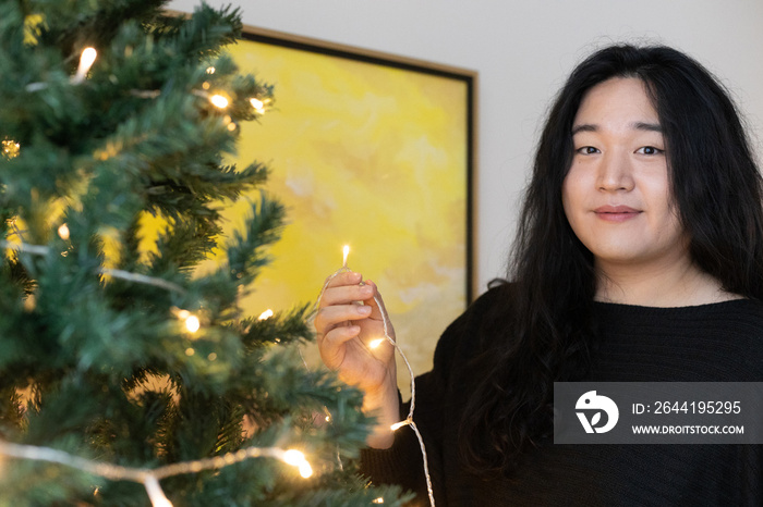 Asian American trans woman decorating for the holidays.