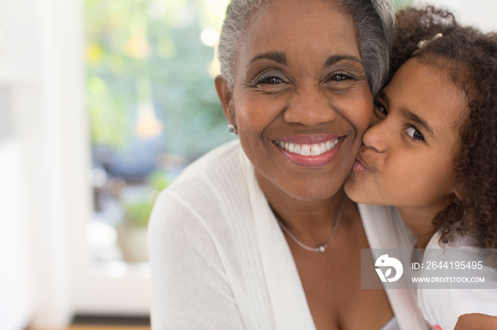 Close up portrait cute granddaughter kissing grandmother on cheek