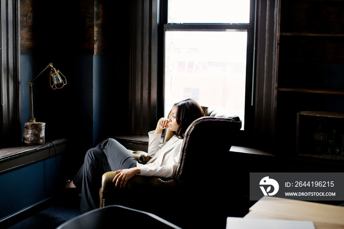 Thoughtful woman sitting in armchair at home