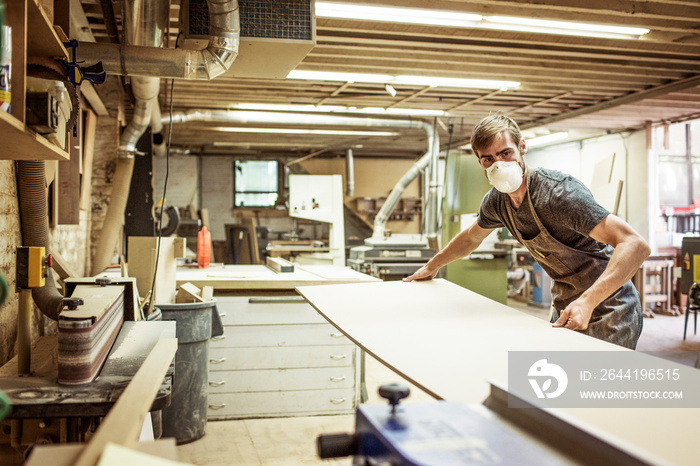 Carpenter wearing mask working in workshop