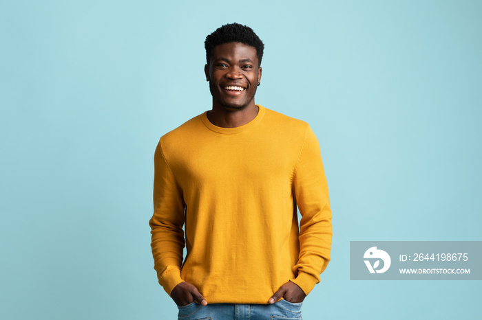 Positive african american guy holding hands in pockets