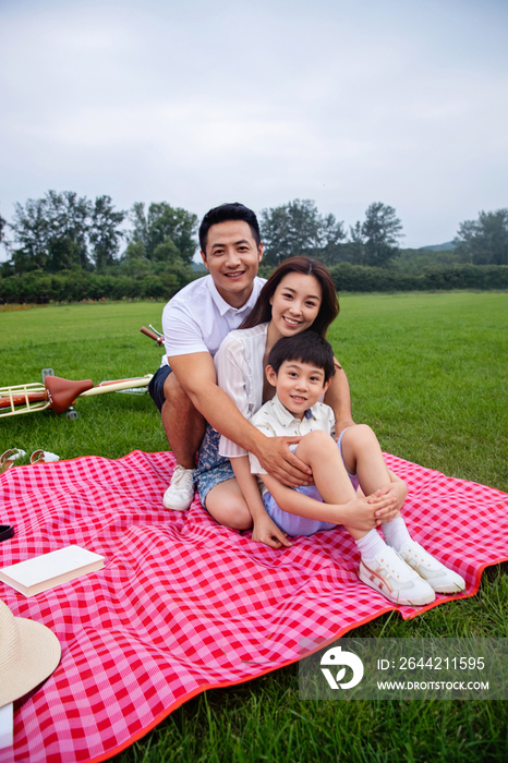 幸福的一家三口坐在野餐垫上