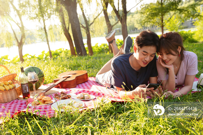 趴在草地上看手机的幸福情侣