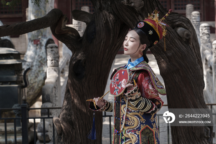 穿清宫服的青年女人站在古树下