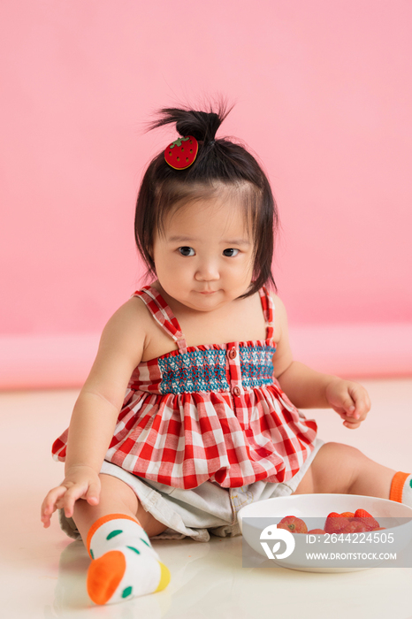 可爱的女宝宝坐着吃草莓