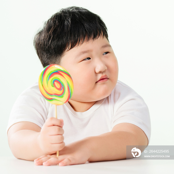 可爱的肥胖小男孩拿着棒棒糖