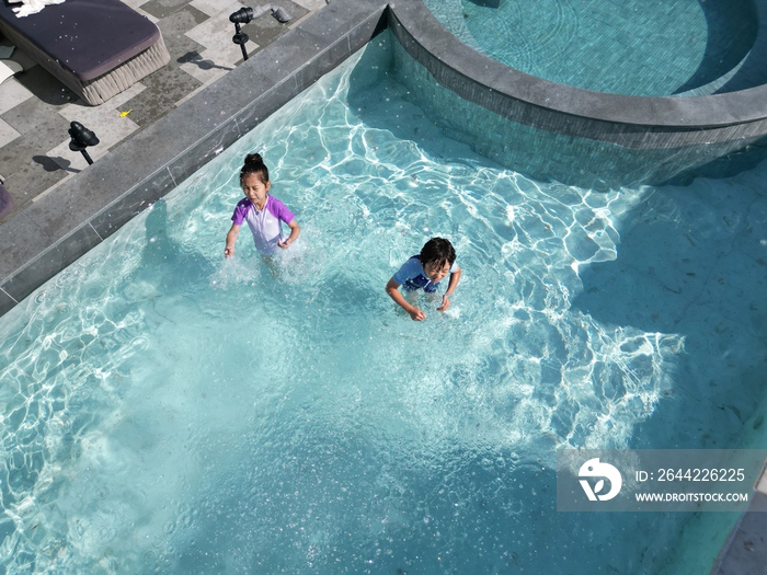 快乐的东方儿童在泳池里戏水