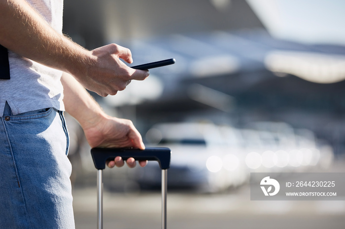 Man holding smartphone and using mobile app against a row of taxi cars. Themes modern technology, ca