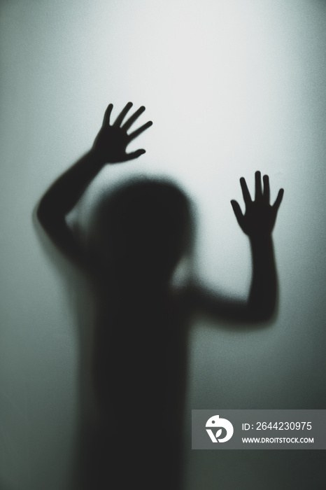 Ghost concept shadow of a child behind the matte glass blurry hand and body soft focus