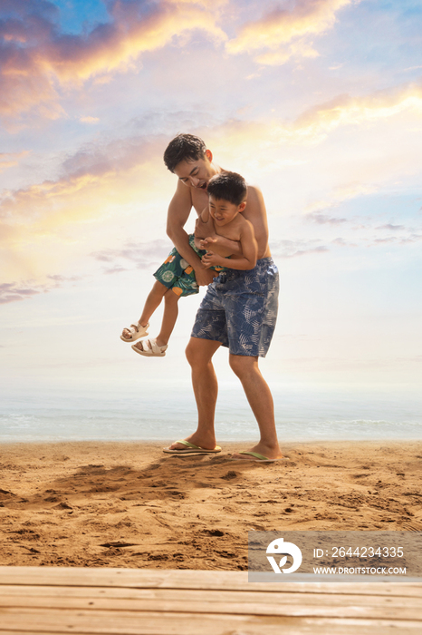 年轻父亲抱着儿子在沙滩玩耍