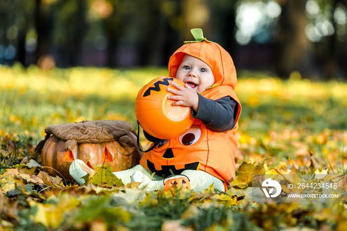 Child in pumpkin suit on background of autumn leaves