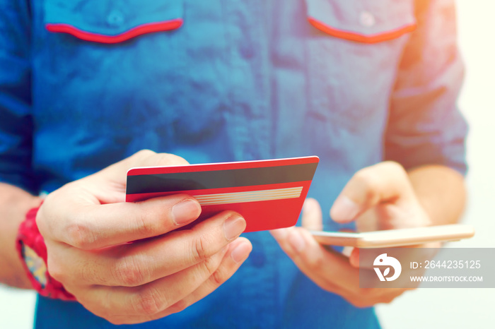 Young man use smartphone and holding credit card with shopping o