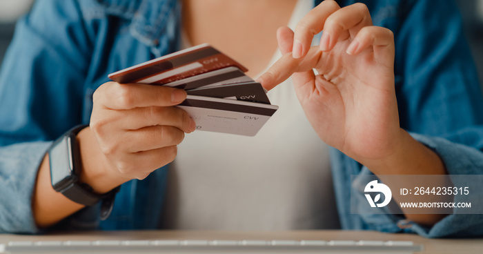 Young asia lady using computer order online shopping product and paying bill with credit card in liv