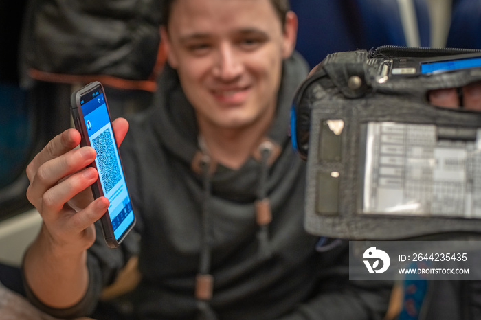 Young sympathetic man shows an electronic ticket conductor on the train on your smartphone. Checking