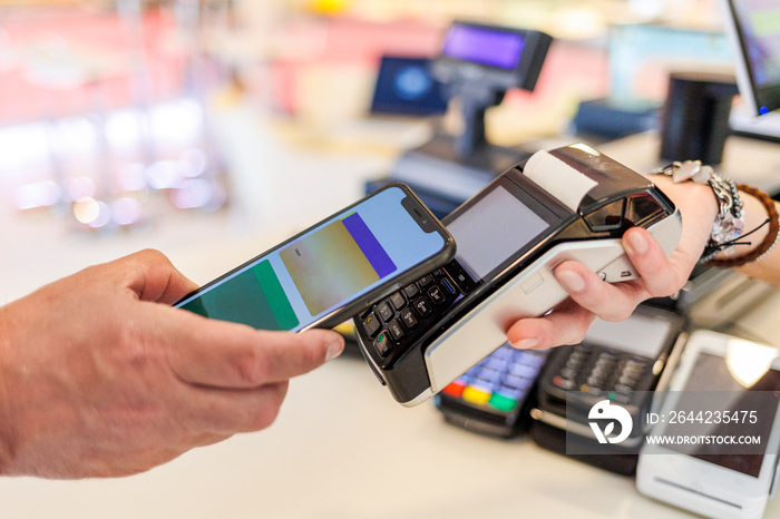 Dettaglio del pagamento con carta di credito con uno smartphone verso il pos di tenuto dalla mano di