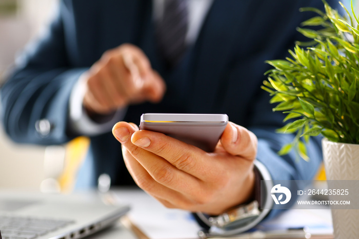 Male arm in suit hold phone