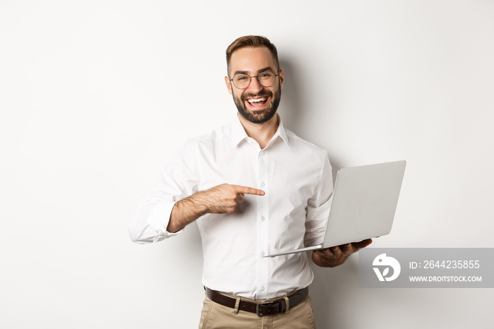 Business. Handsome manager in glasses working on laptop, pointing at computer and smiling pleased, s