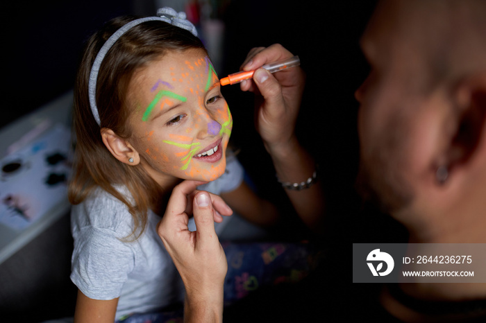 Daughter and father paint a face, having fun, leisure together at home