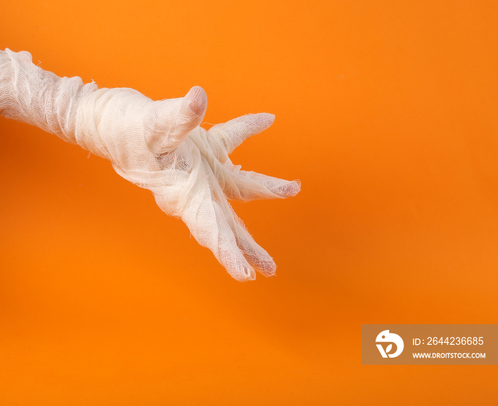 Mummys hand wrapped in white bandages on an orange background. Happy Halloween. Trick or Treat