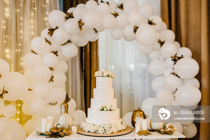 Delicious wedding reception. Cake on a background balloons. Decorated table for wedding. White ballo