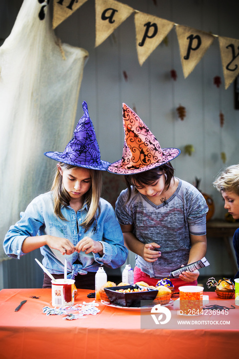 Children decorating muffins at table during Halloween party