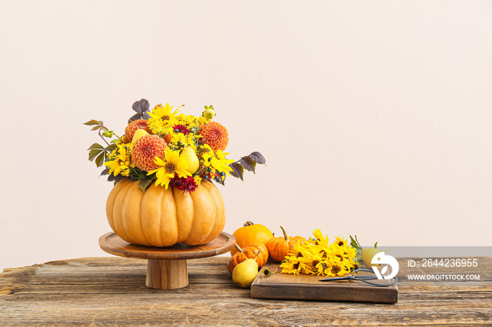 Beautiful autumn bouquet in pumpkin on table against light background