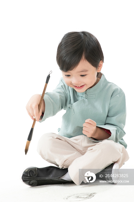 可爱的小男孩坐在地上用毛笔写字