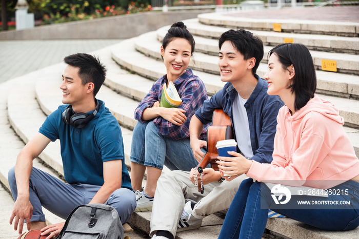 年轻的大学生坐在台阶上闲聊